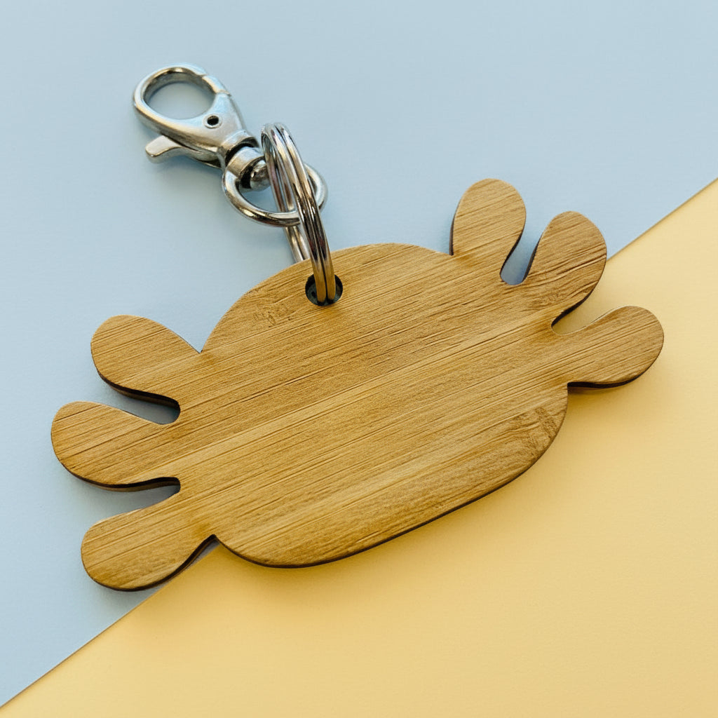 Wooden keychain shaped like a Axolotl on a textured surface