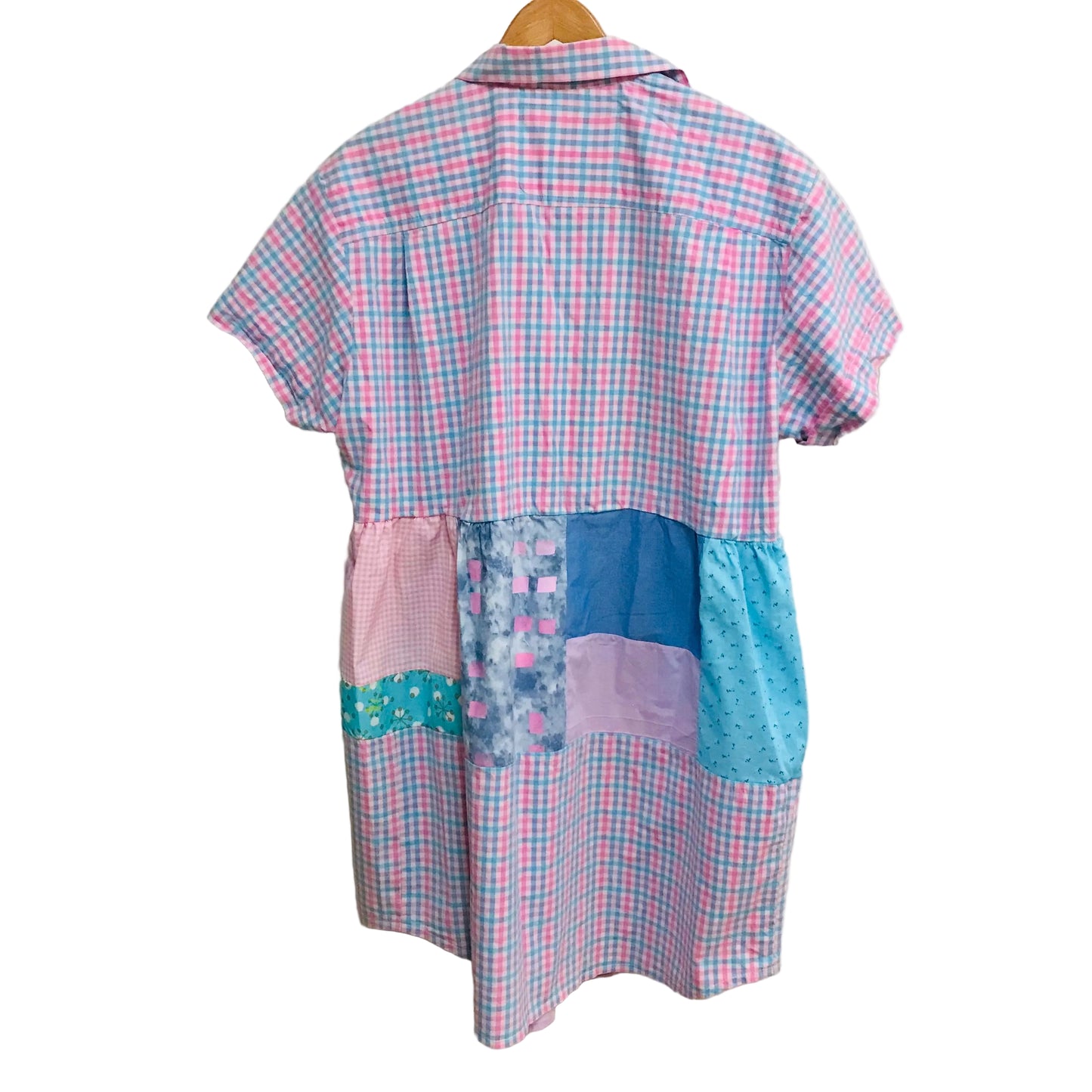 Patchwork dress with plaid pattern on a hanger against a white wall