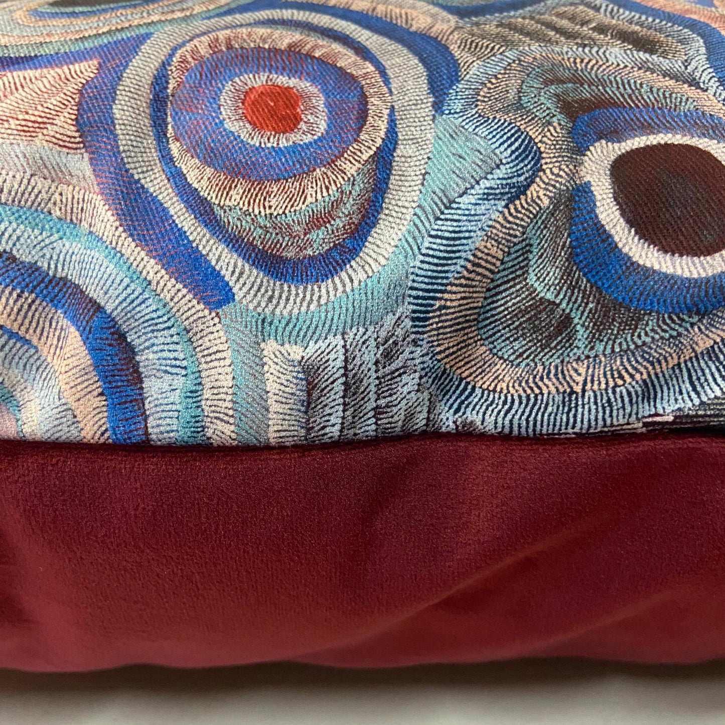 Textile with circular patterns in blue, brown, and beige on a red background