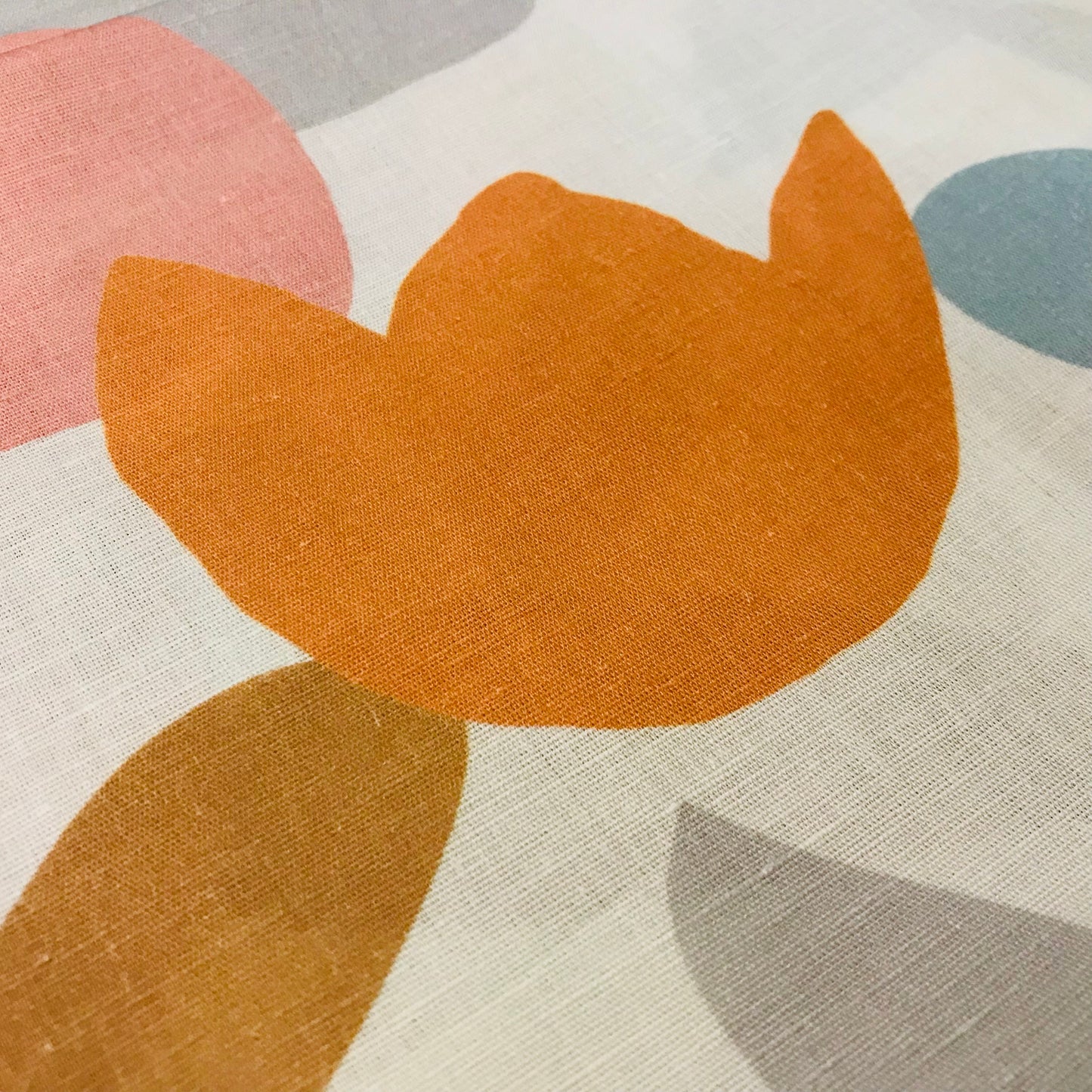 Close-up of a textured fabric with abstract shapes in orange, pink, and gray.