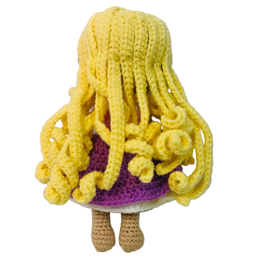 Crocheted doll with yellow hair and purple outfit on a white background