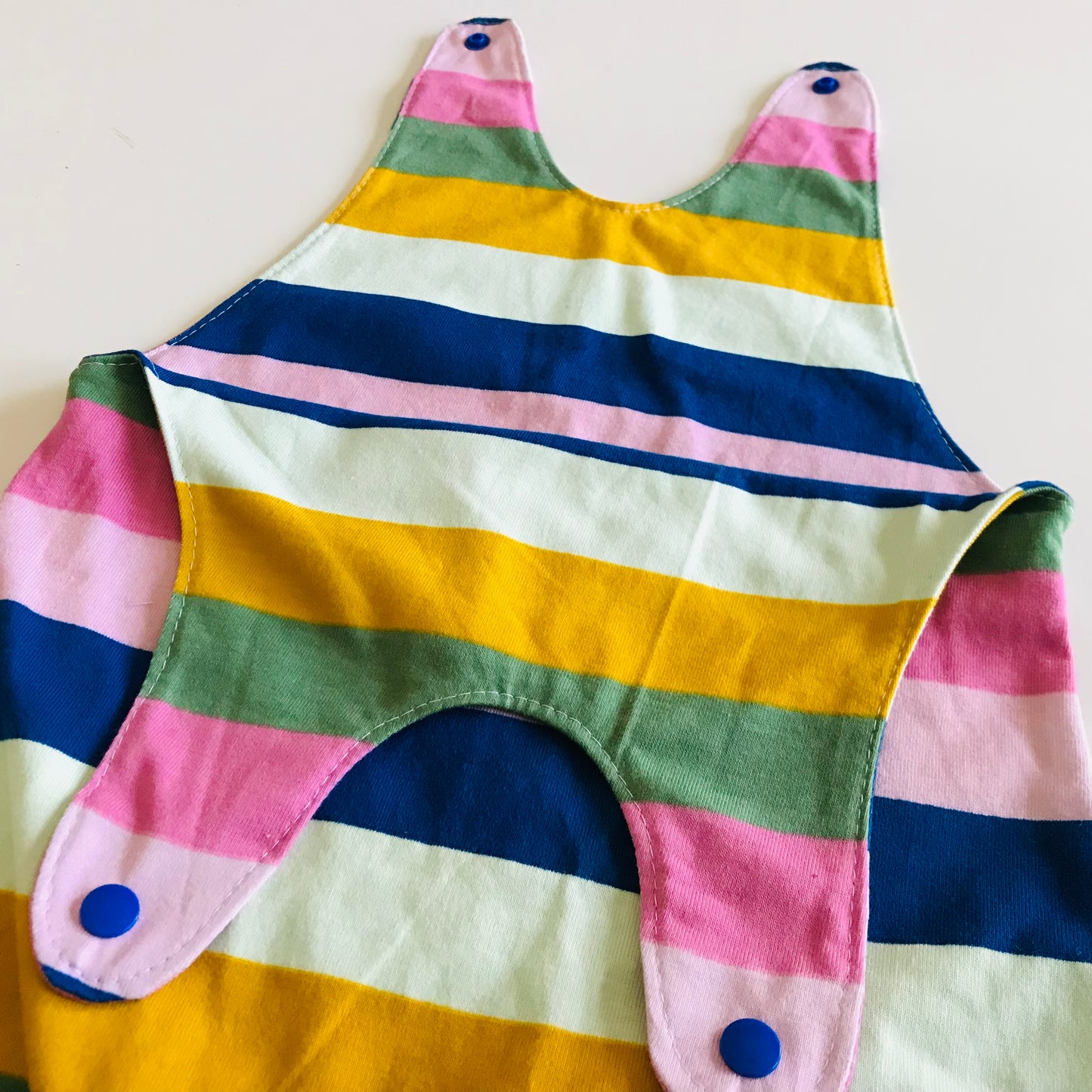 Colorful striped baby romper with blue buttons on a white background