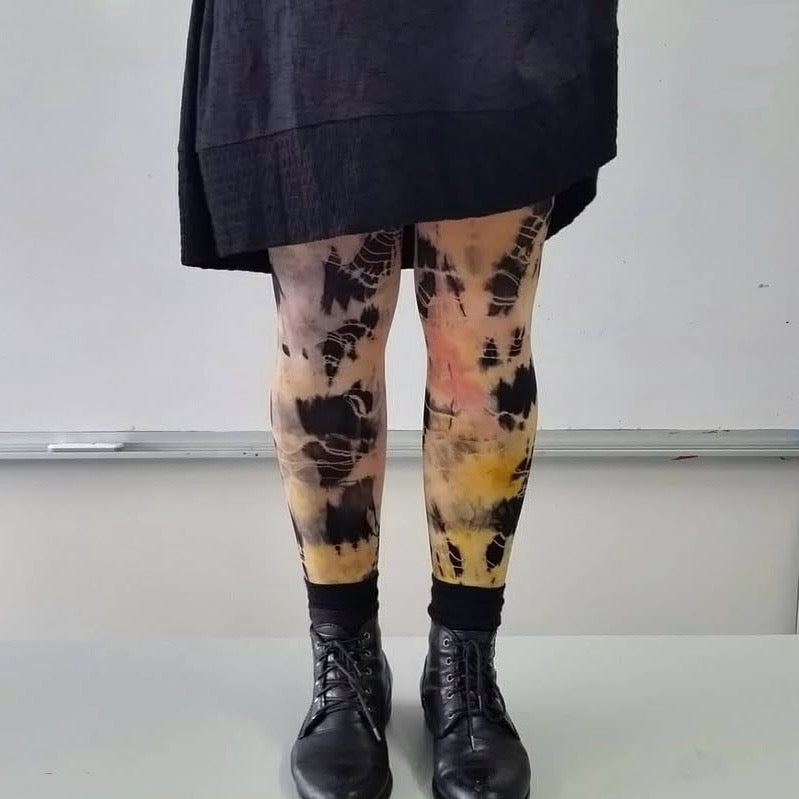 Person wearing tie-dye leggings with black boots on a white background