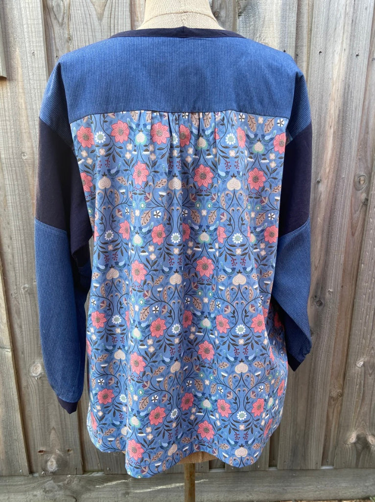 Back of Blue floral-patterned tunic top on a mannequin against a wooden fence background
