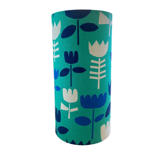 A drum shade with a mid-century modern floral pattern in teal, navy blue, and cream, displayed on a white background