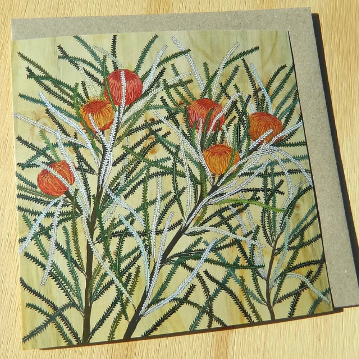 Greeting card with embroidered design of red berries and green leaves on a wooden surface