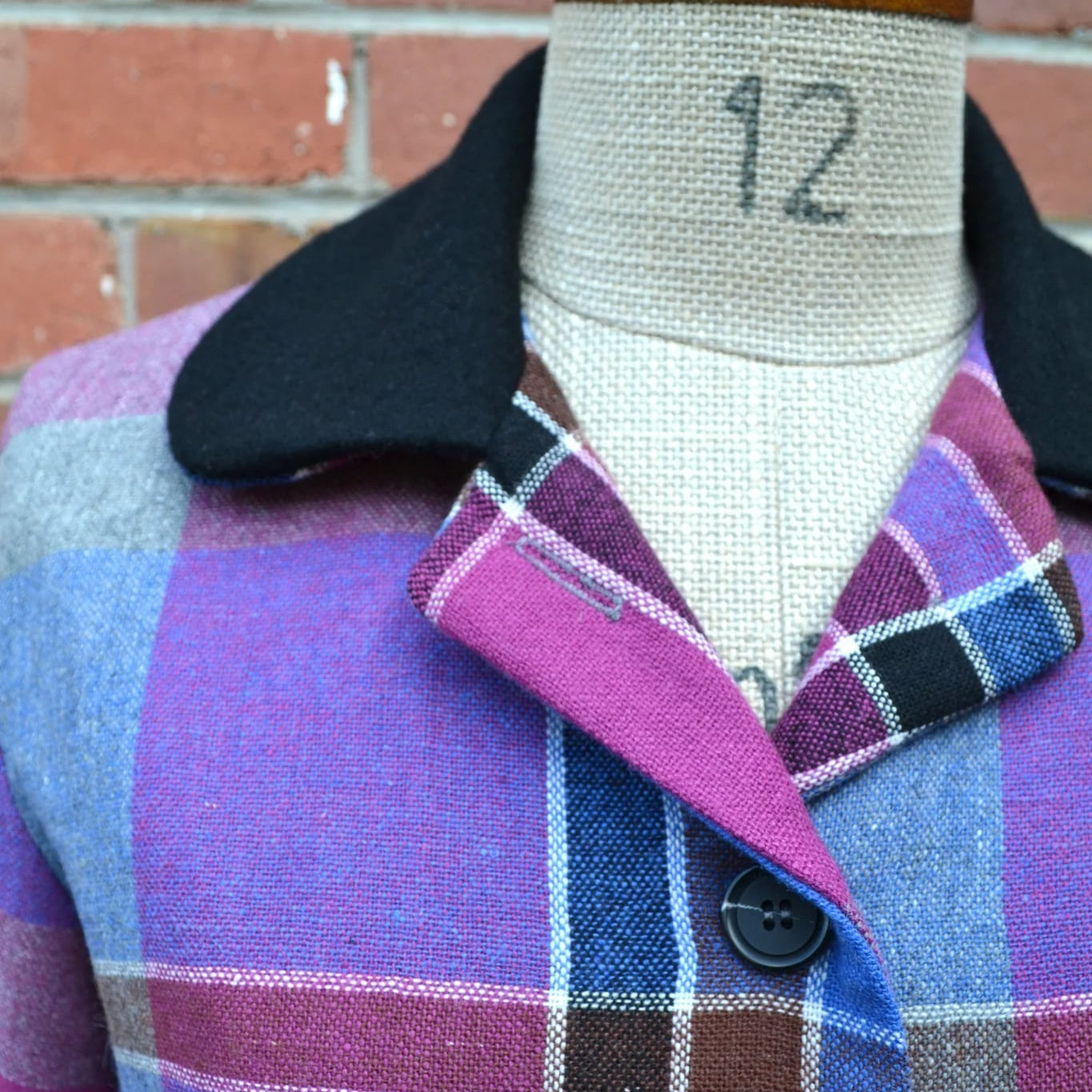 Plaid cropped jacket on a mannequin with a brick wall background