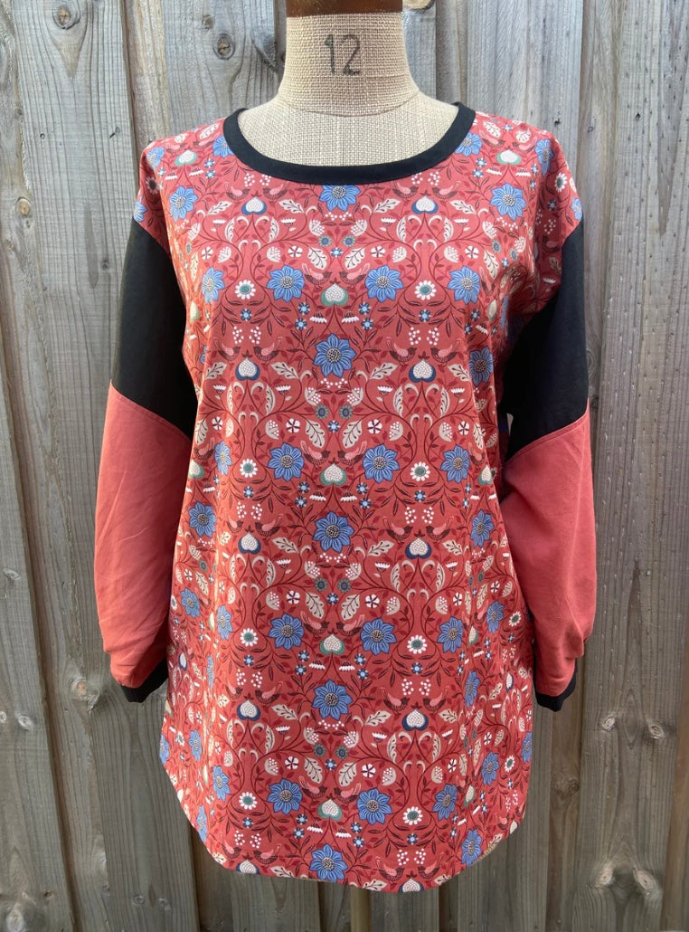 Floral patterned tunic top on a mannequin against a wooden background