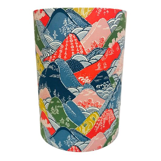 Cylindrical lamp shade with colorful mountain and wave pattern on a white background