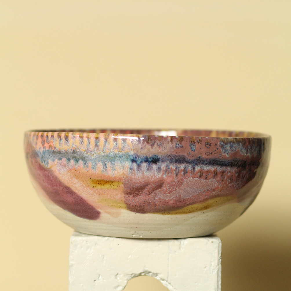 Ceramic bowl with multicolored glaze on a beige background