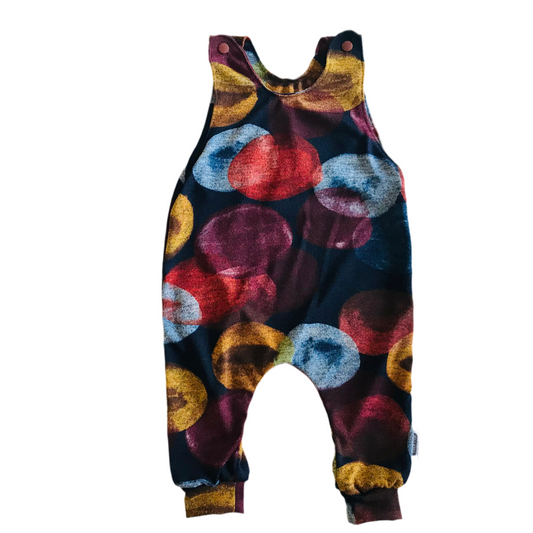 Colorful handmade children's long romper overalls with abstract pattern on a white background