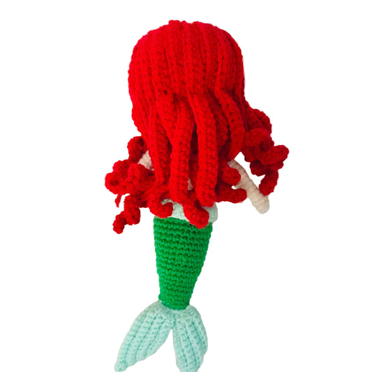 Crocheted mermaid toy with red hair and a green tail on a white background