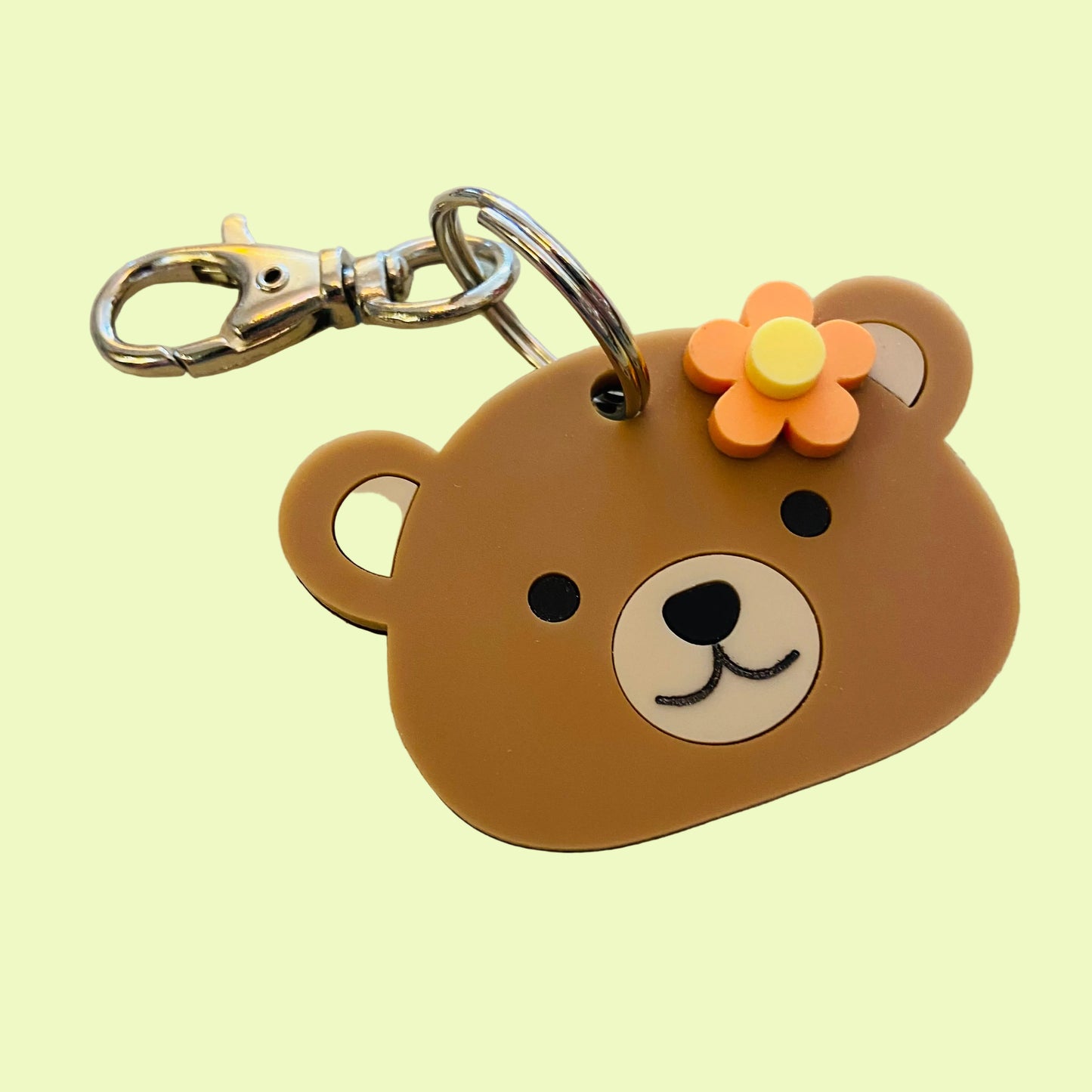 Brown bear-shaped keychain with a flower on a beige background