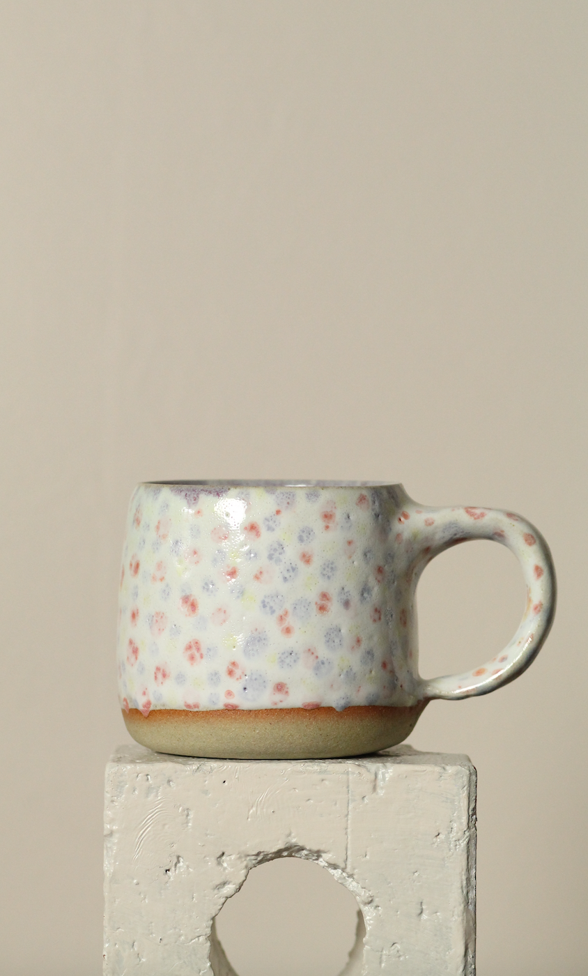 Ceramic mug with dotty pattern on a beige background