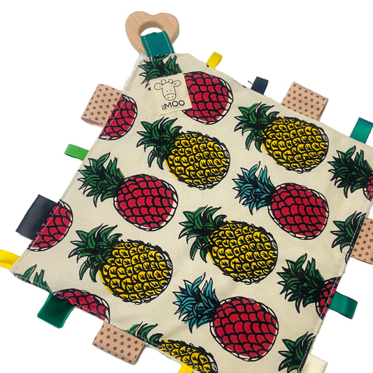 A colorful baby taggie toy with a variety of fabric tags and a wooden ring, backed with an organic bamboo toweling.