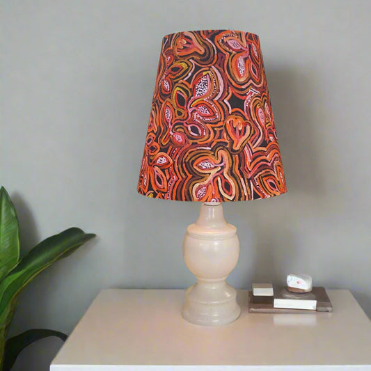 Lamp with a colorful patterned shade on a white surface against a gray wall.