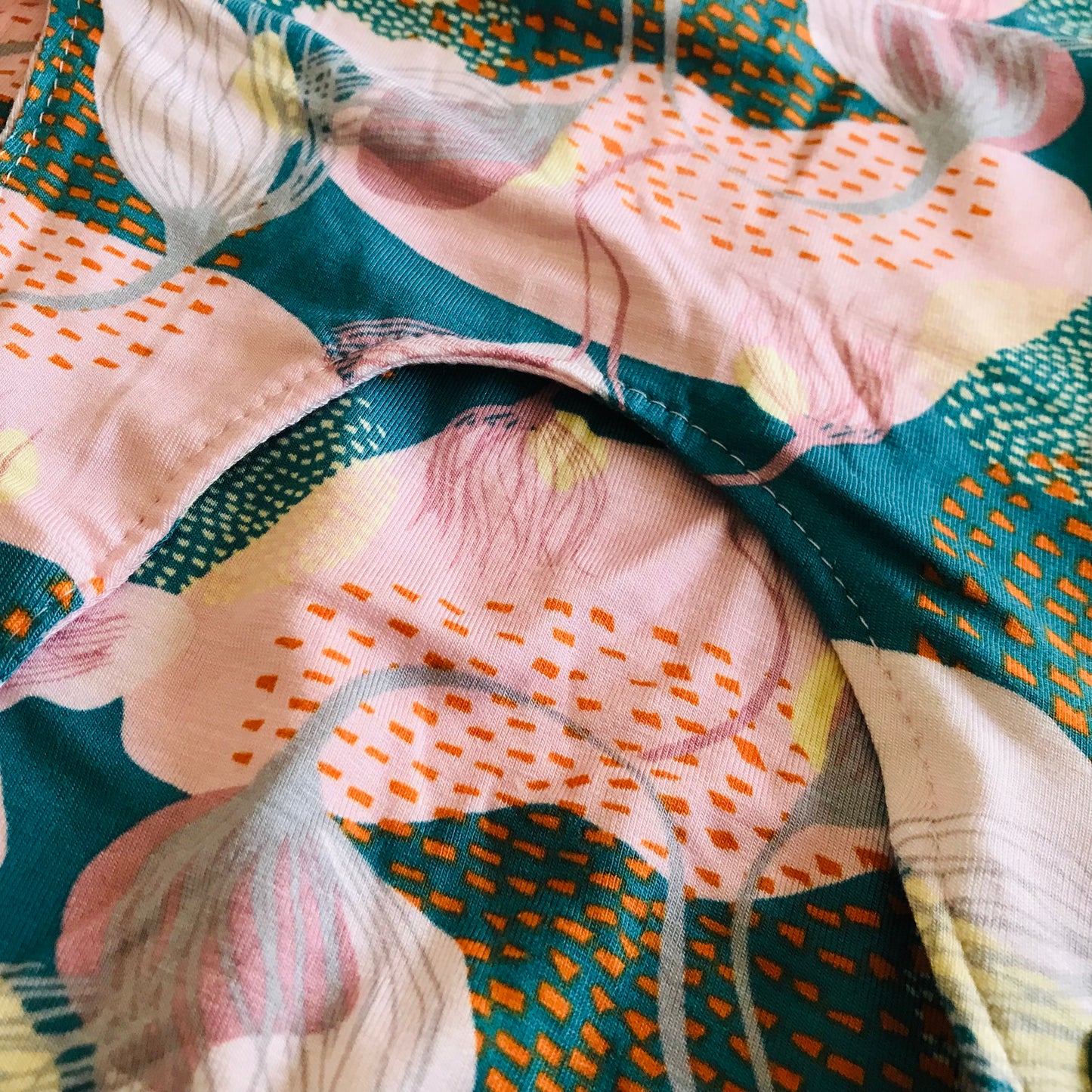 Close-up of a floral fabric with pink, green, and orange colors.