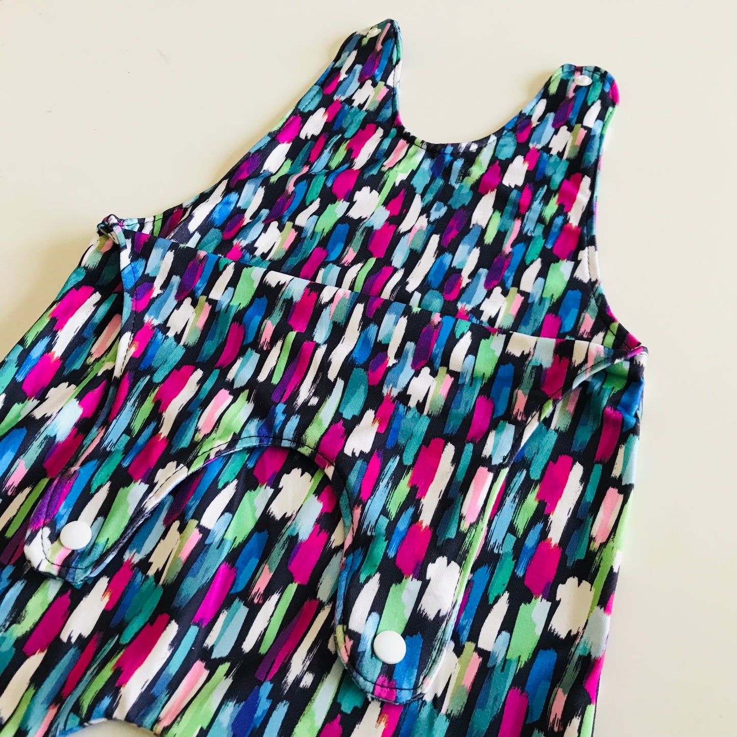 Colorful sleeveless baby romper with abstract pattern on a light background