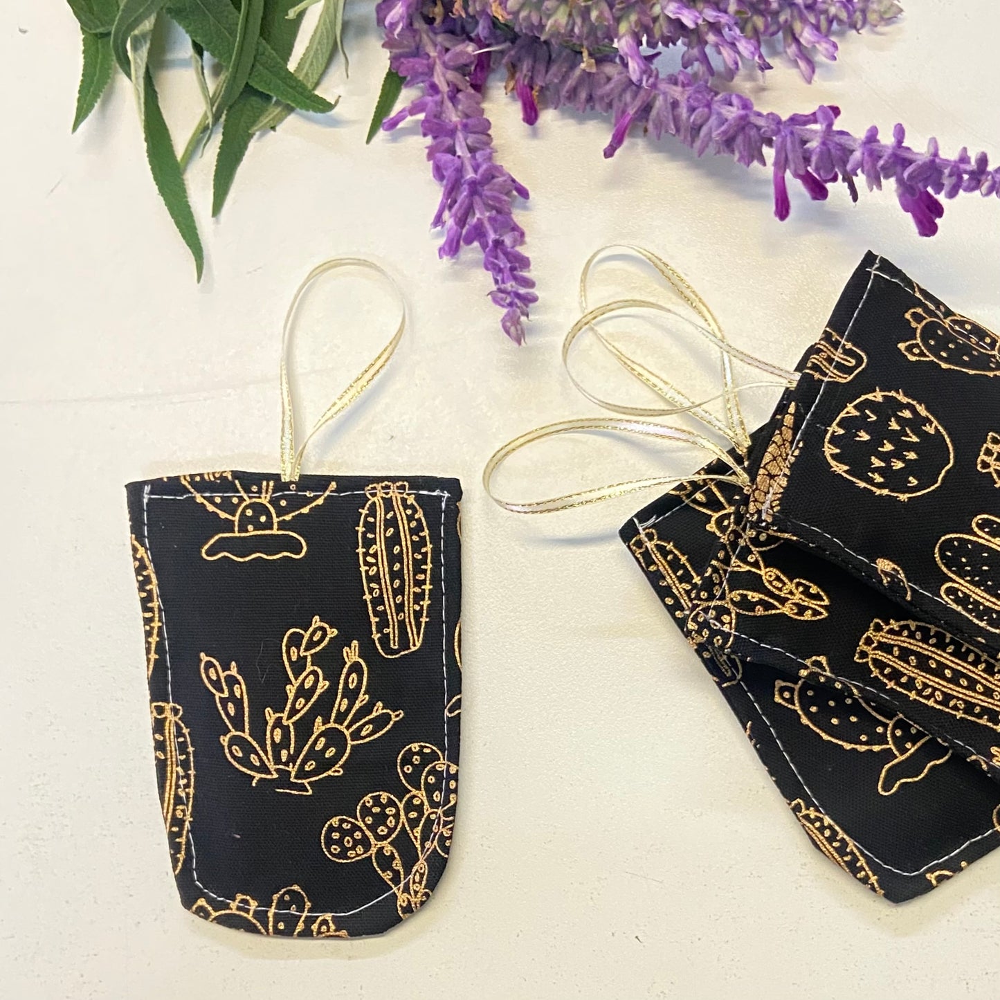 small hanging pouch filled with lavender to hang in your wardrobe or place in your clothing drawers to leave the space gmelling fresh. This set of four pouches have a gold on black cactus textile.