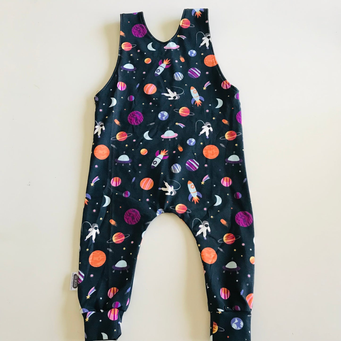 Children's overalls with space-themed print on a white background