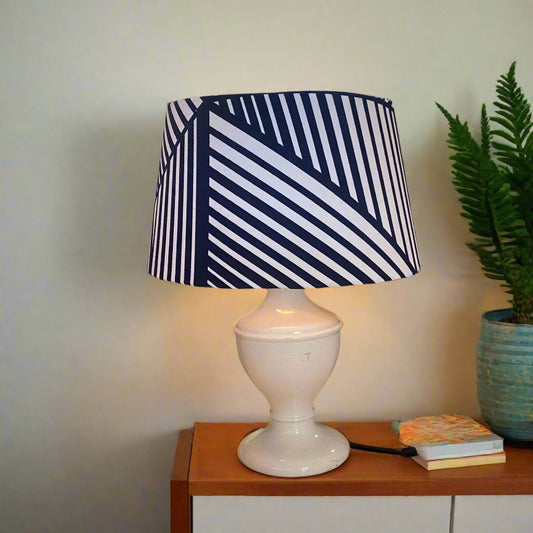 Table lamp with a striped navy and white shade on a wooden surface.