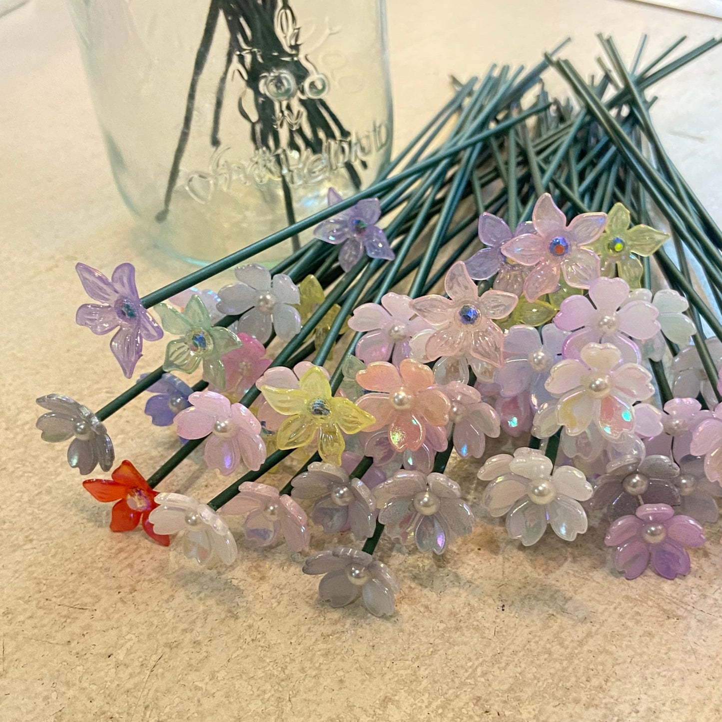 Artificial flowers in a clear vase on a textured surface with a blurred background
