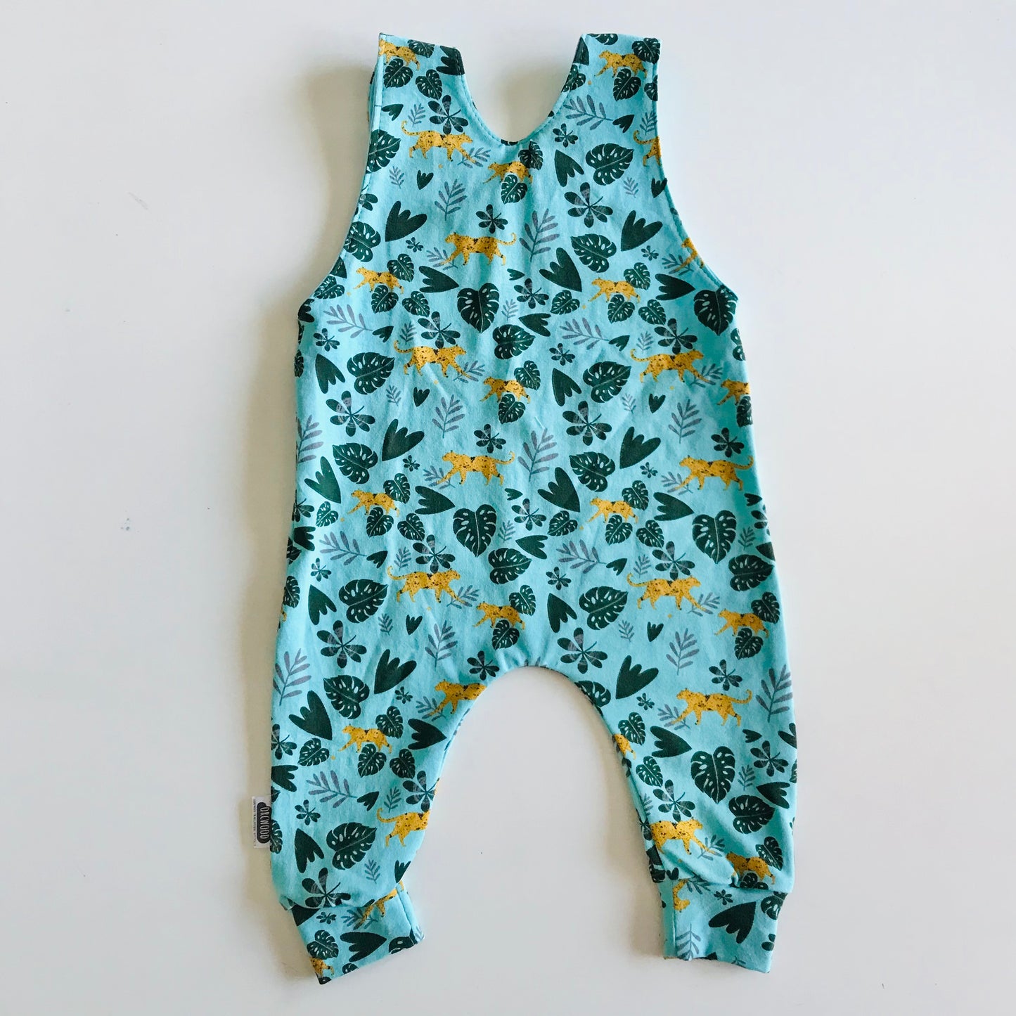 Children's long romper overalls with a cheetah and jungle leaves print on light blue background
