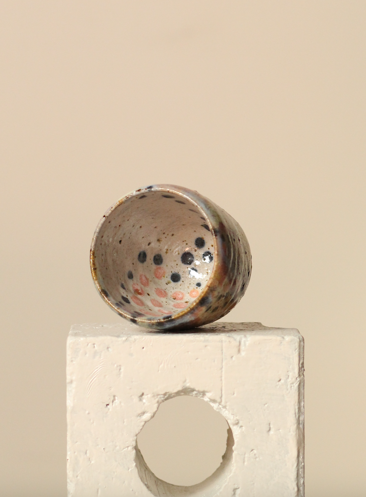 Ceramic espresso cup with speckled design on a beige surface