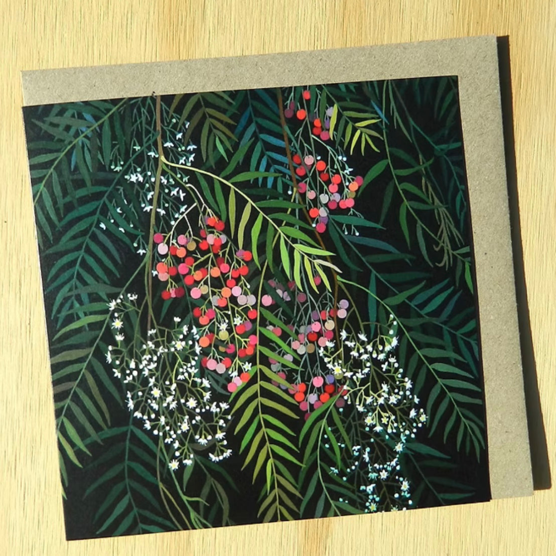 Greeting card with leaf and berry design on a wooden surface