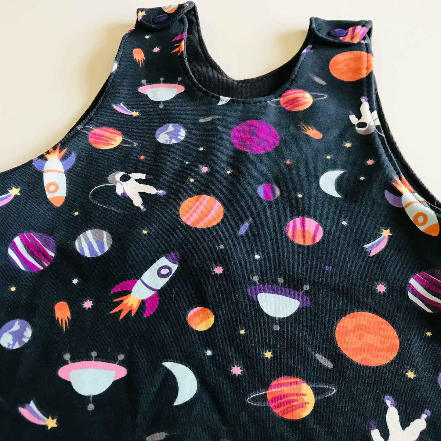 Children's romper with space-themed print on a plain background