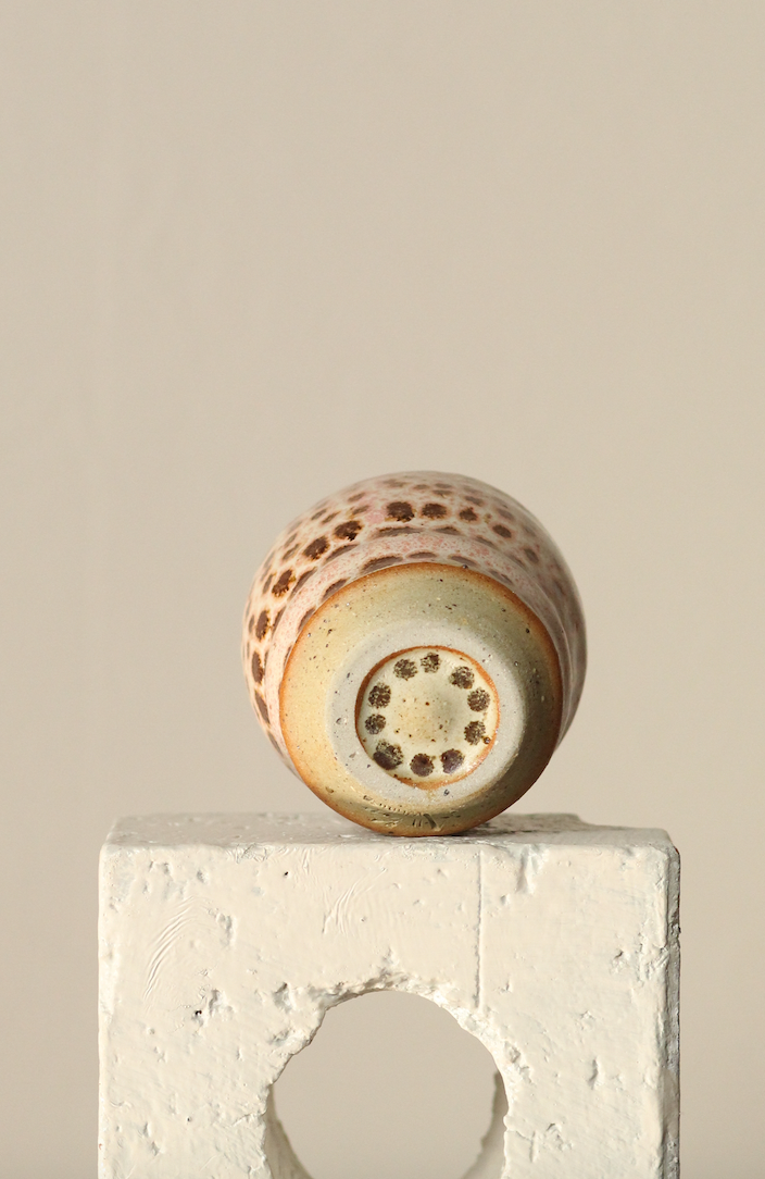 Ceramic cup with textured surface on a concrete block against a beige background