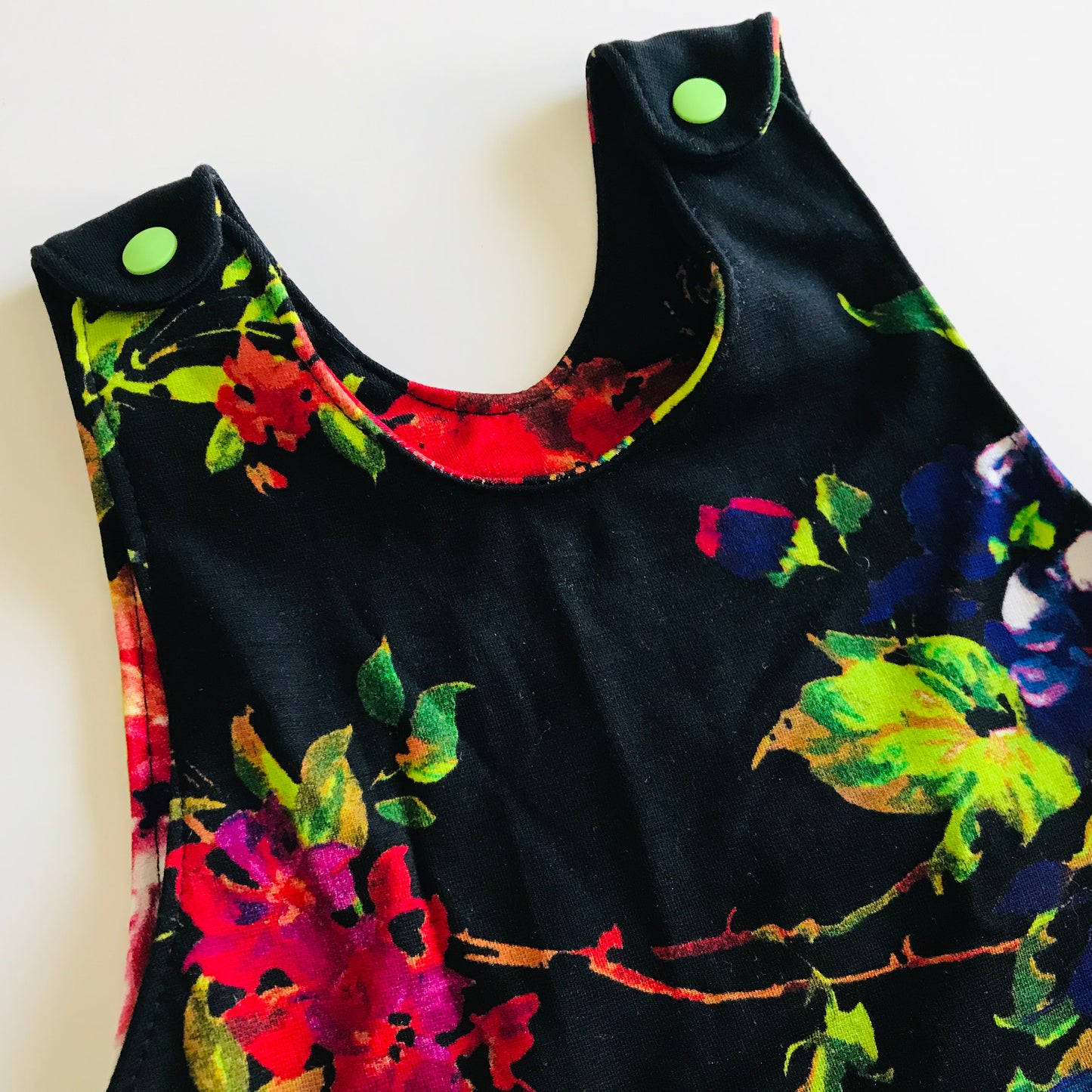 Black sleeveless baby romper with colorful floral patterns on a white background