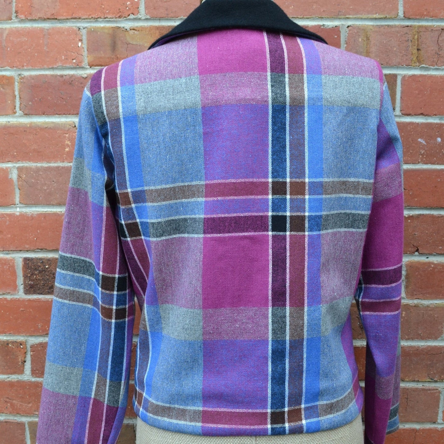 Plaid cropped jacket on a mannequin against a brick wall
