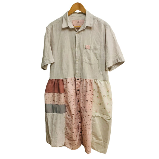Patchwork dress made from va beige shirt and floral shirt on a hanger against a white wall.