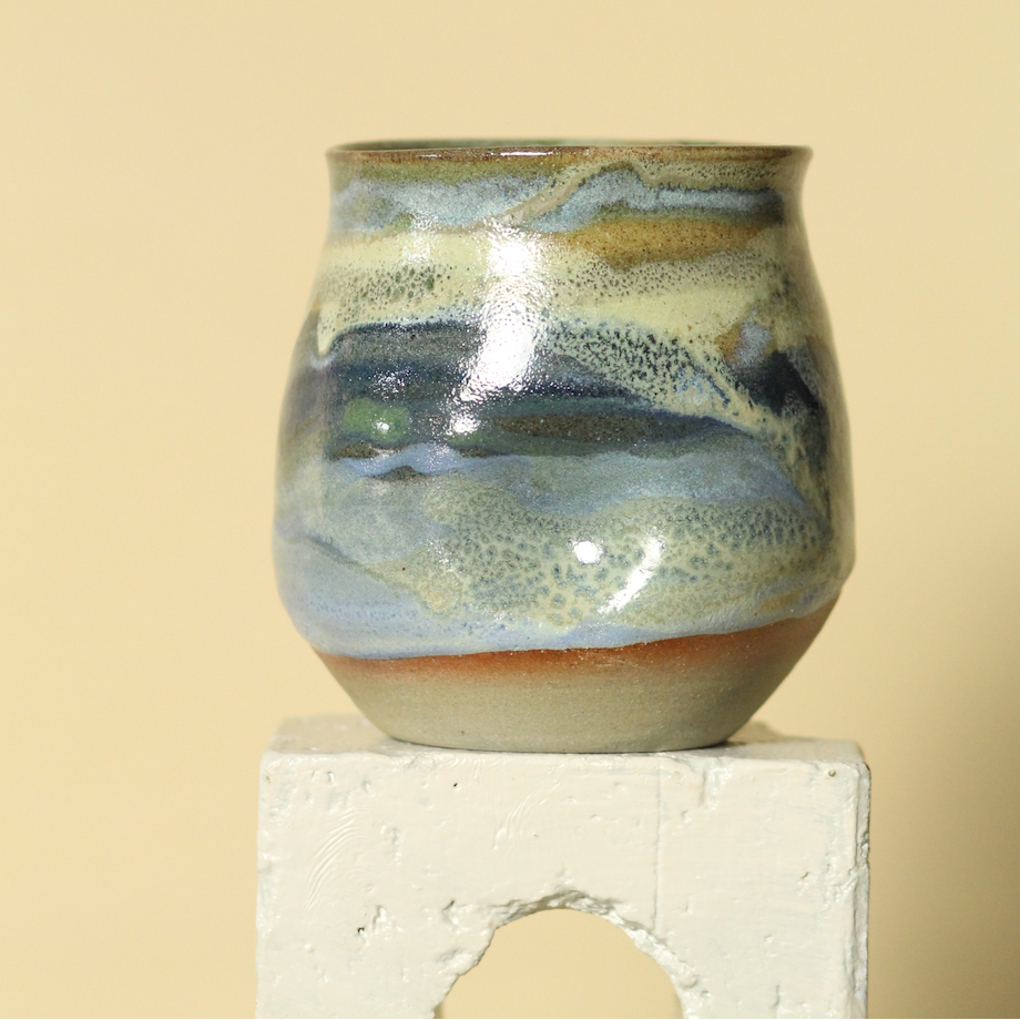 Ceramic cup with multicolored glaze on a beige background