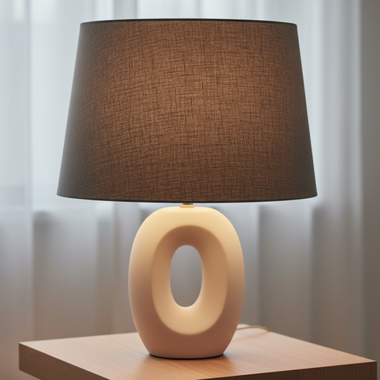 Table lamp with a grey shade and beige base on a wooden surface.
