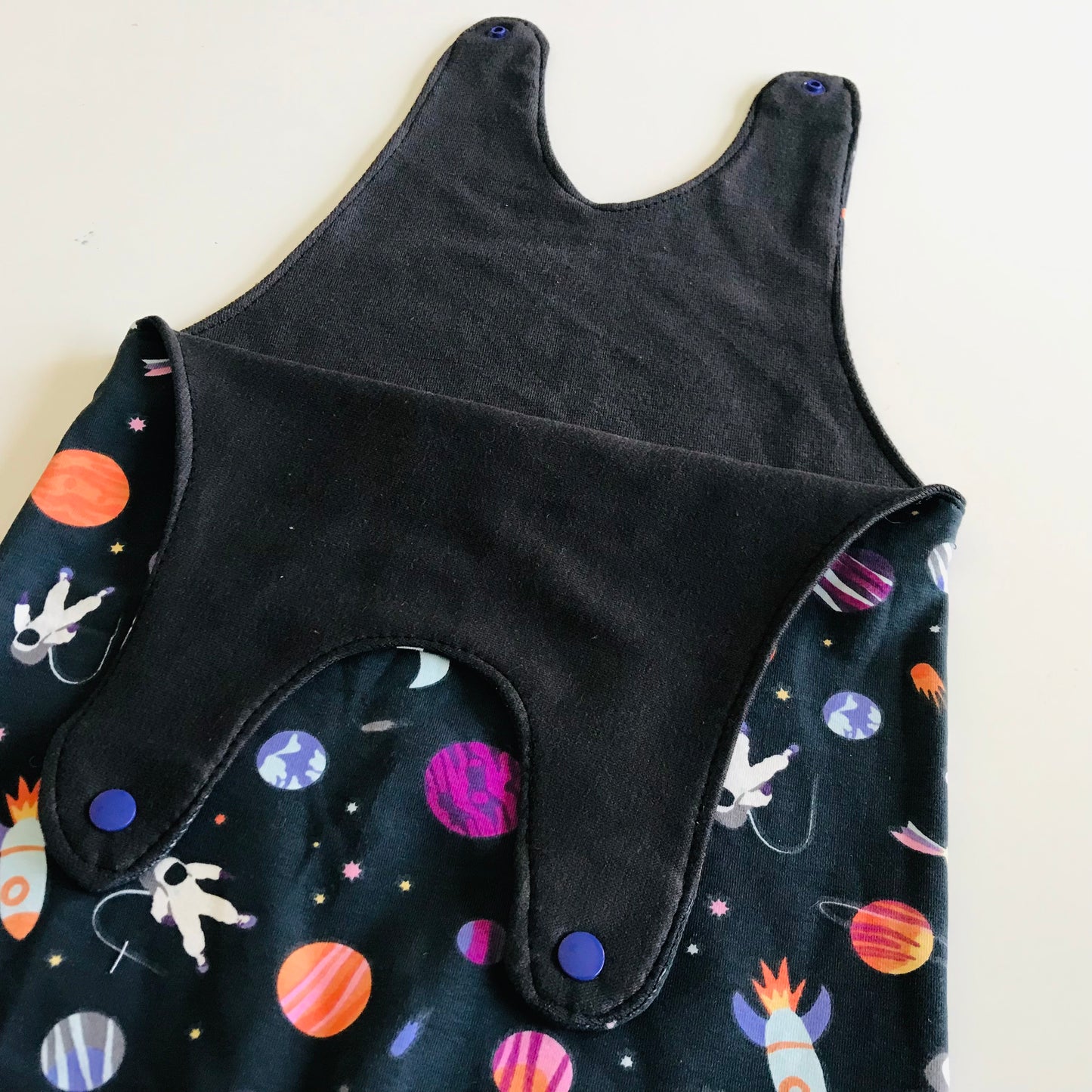Black sleeveless garment with space-themed pattern on a white background
