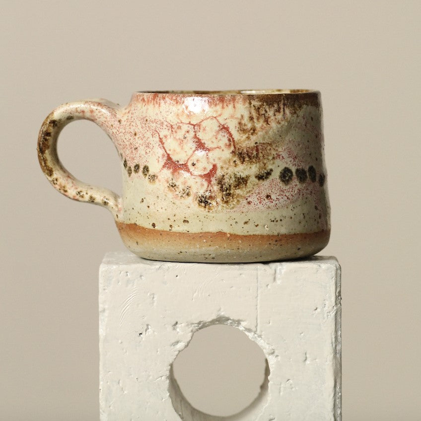 Ceramic mug with speckled glaze on a neutral background
