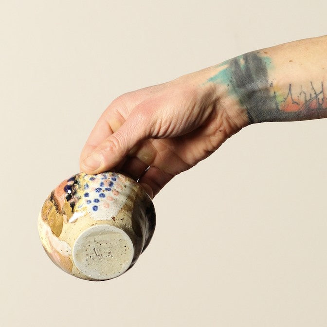Hand holding a ceramic bowl with a textured surface against a beige background