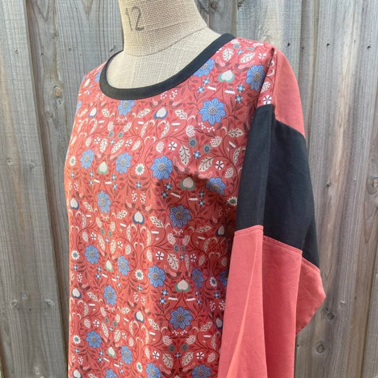 Floral-patterned tunic top on a mannequin against a wooden fence background