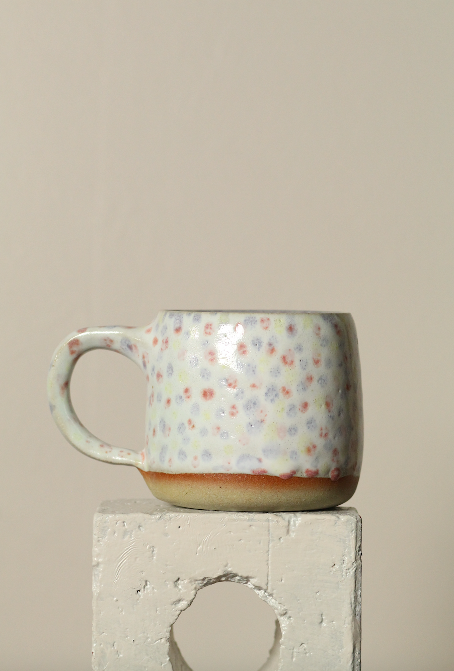 Ceramic mug with dot pattern on a beige background