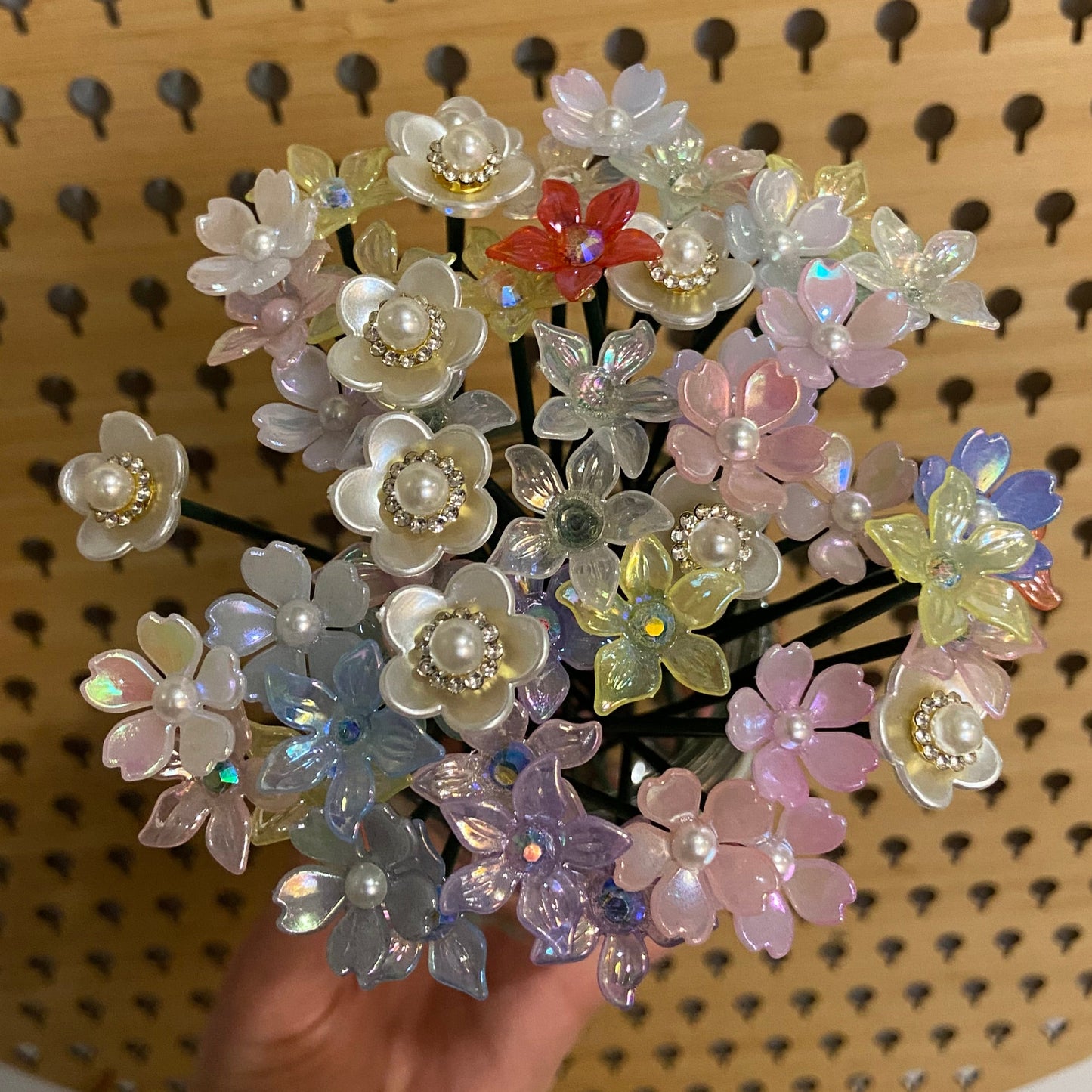 Decorative flower stems held by a hand against a wooden background