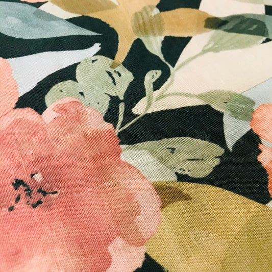 Close-up of a floral pattern with pink, green, and black colors on a textured fabric background.