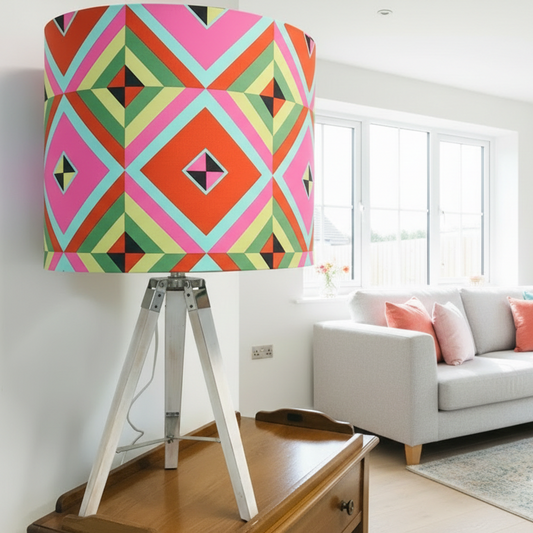 Colorful geometric-patterned lampshade on a tripod stand against a white wall.