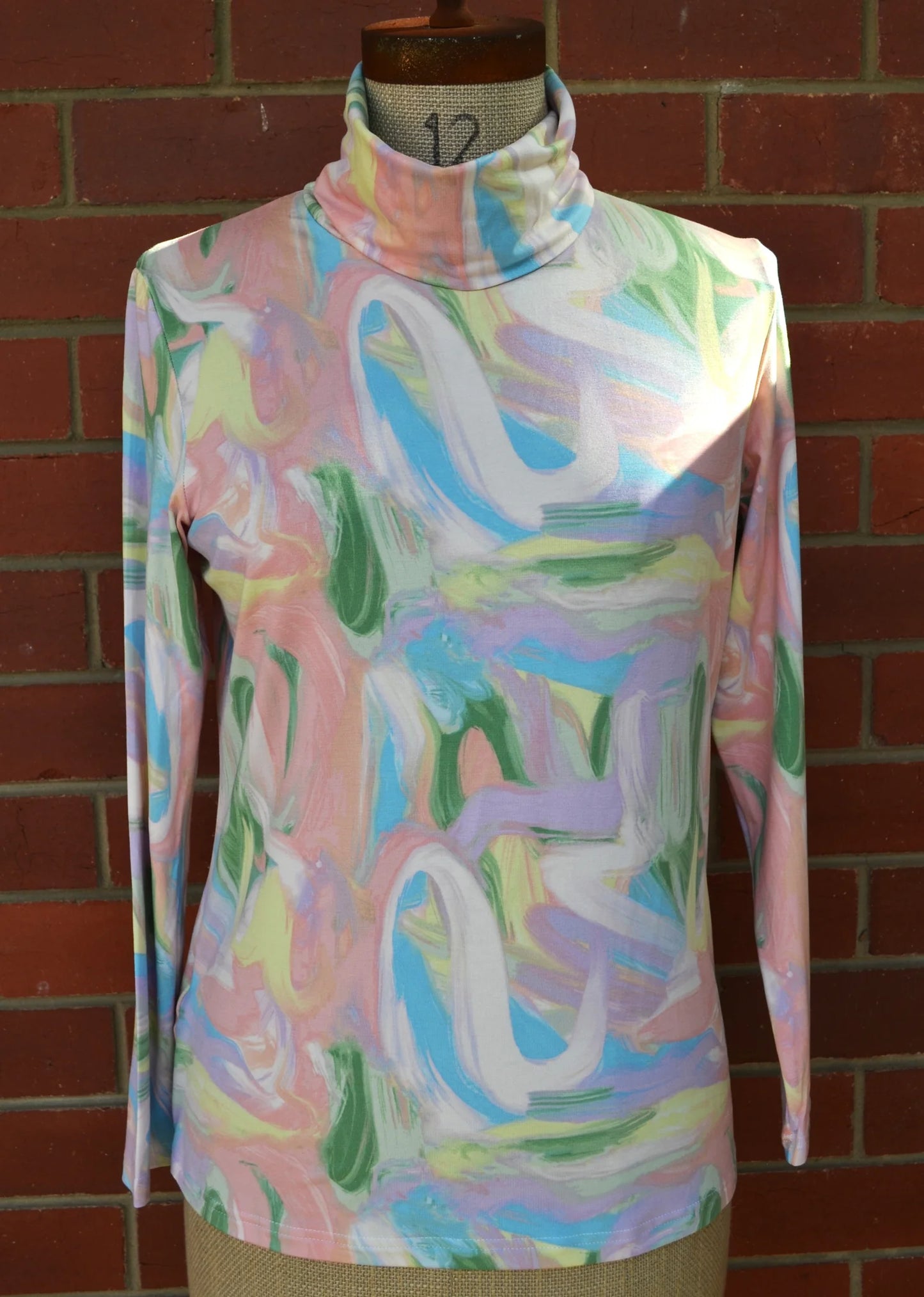 Colorful abstract patterned skivvi on a mannequin against a brick wall.