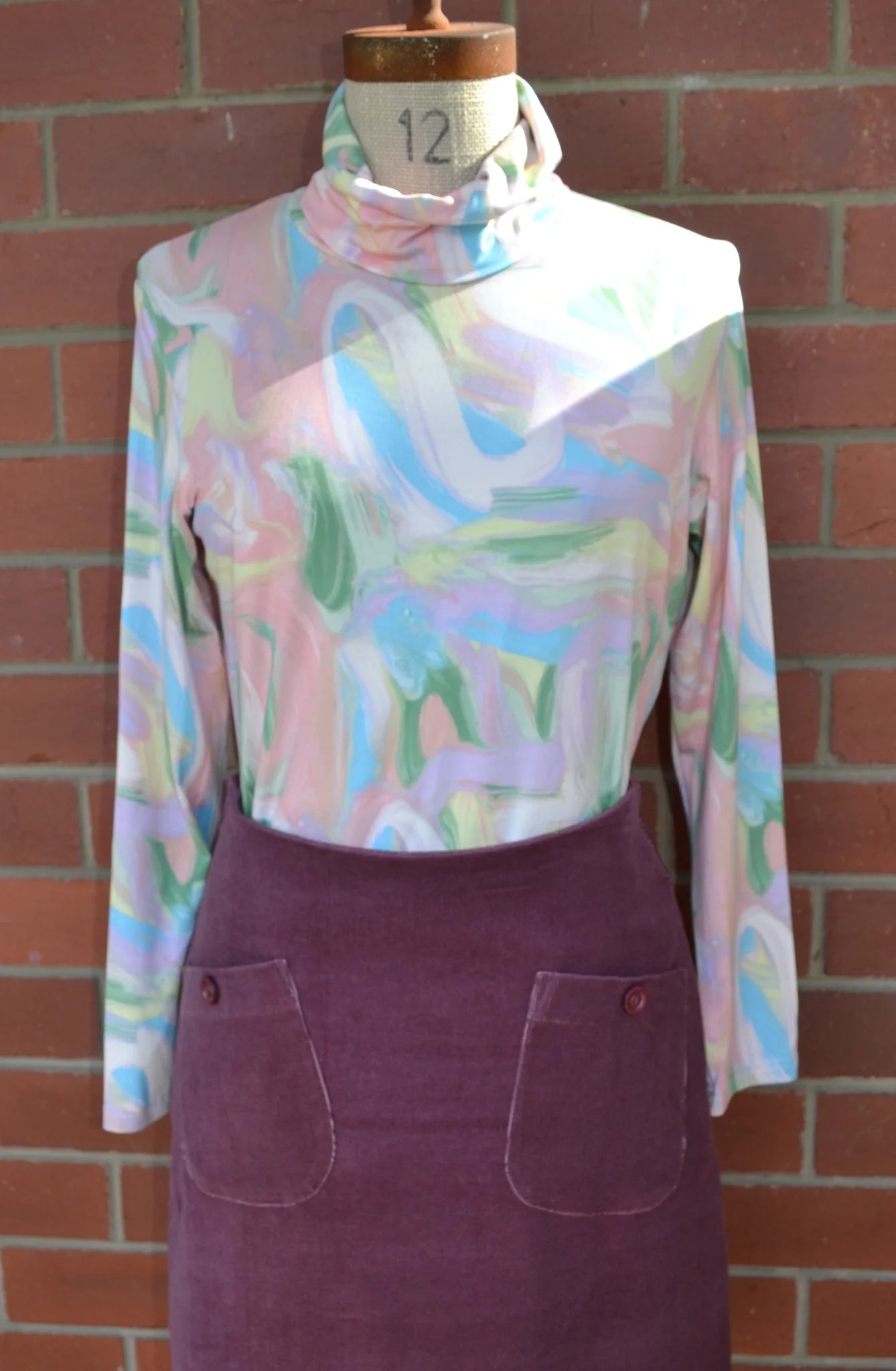 Pastel patterned skivvi on a mannequin against a brick wall