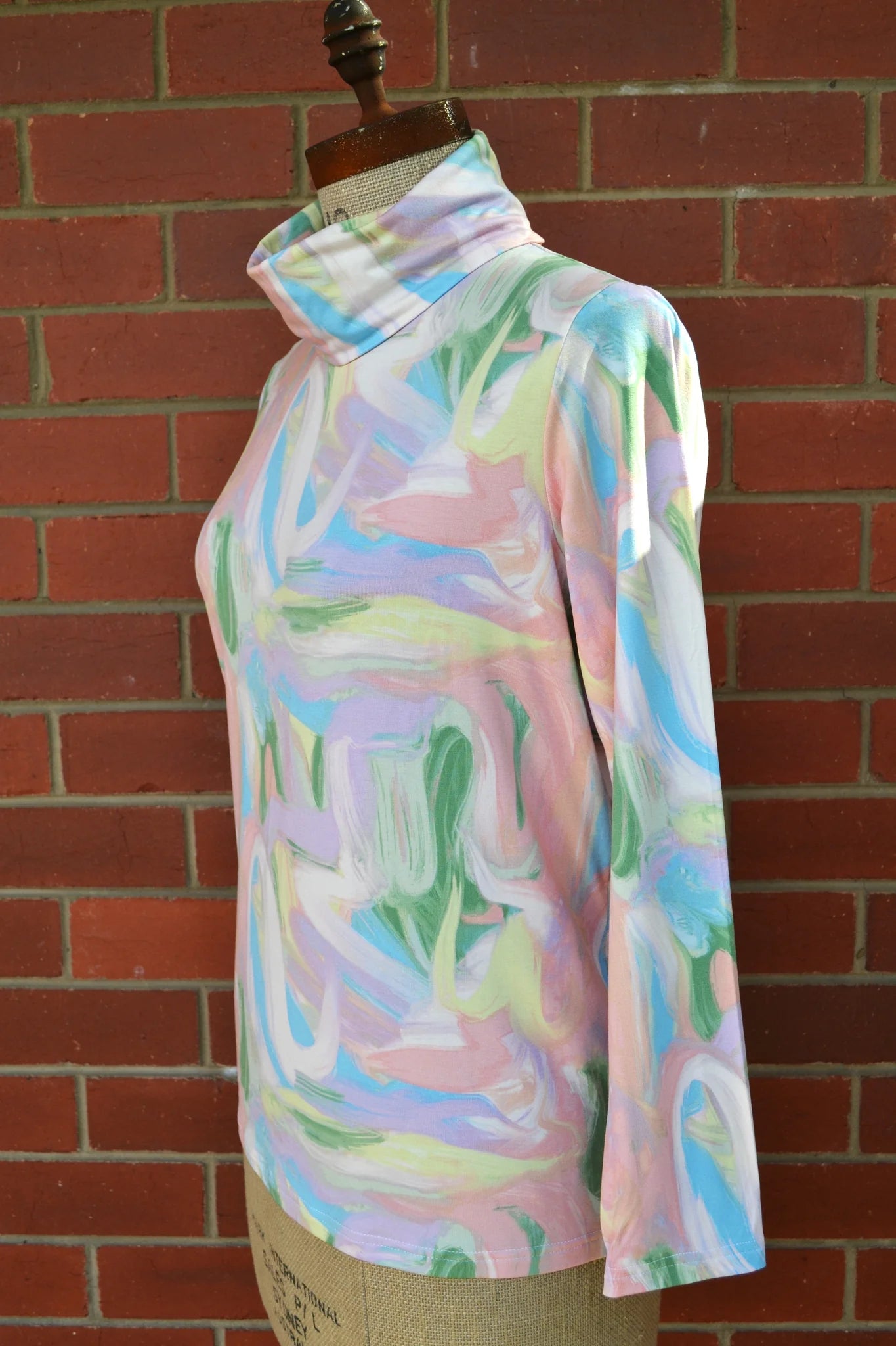 Pastel abstract patterned skivvi on a mannequin against a brick wall.