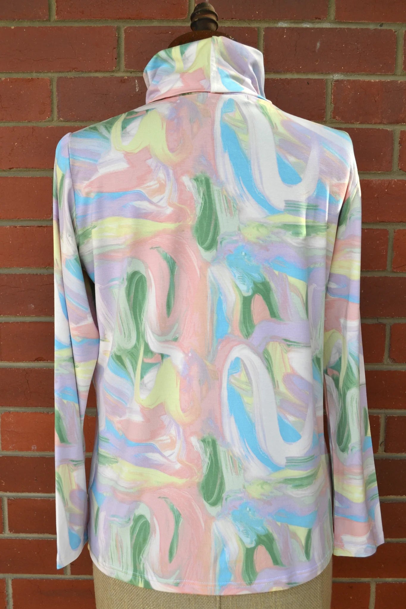 Colorful abstract patterned skivvi on a mannequin against a brick wall.