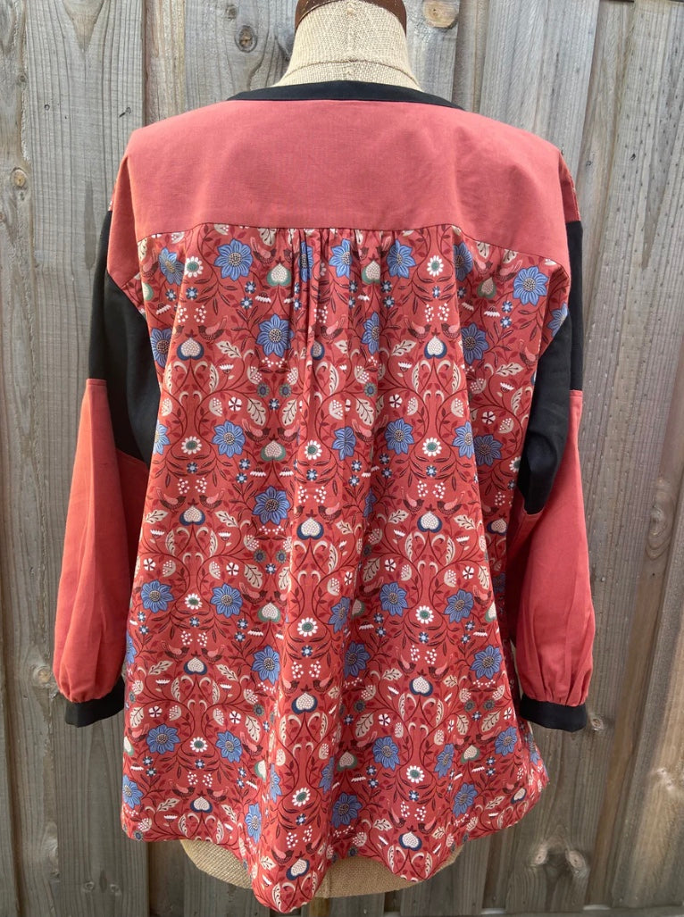 back of red floral patterned tunic top on a mannequin against a wooden background