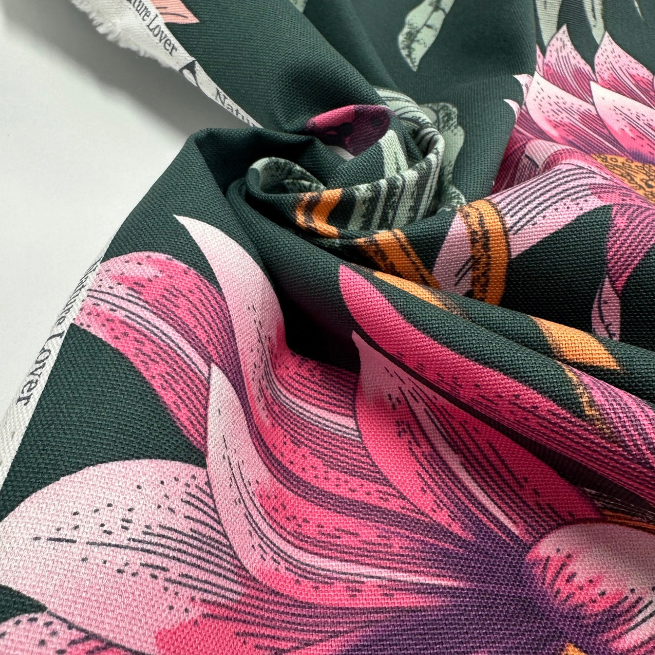 Close-up of floral fabric with pink and green leaves on a dark background